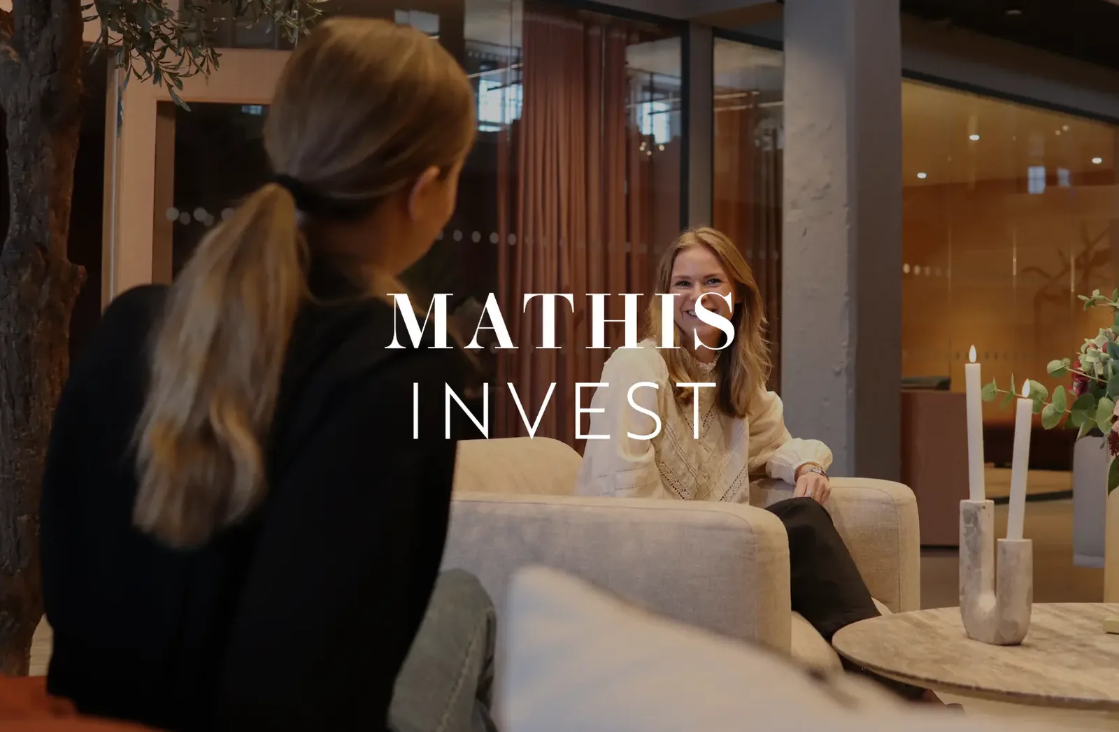 Två kvinnor samtalar i en soffgrupp på Mathis Invest med logotypen över bilden